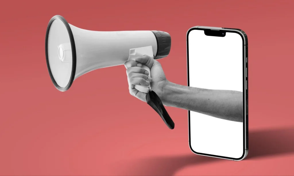 Creative concept of a hand holding a megaphone from a smartphone, symbolizing the power of digital marketing, mobile outreach, and online promotion.